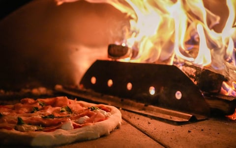 Pizza cooking in wood-fired oven