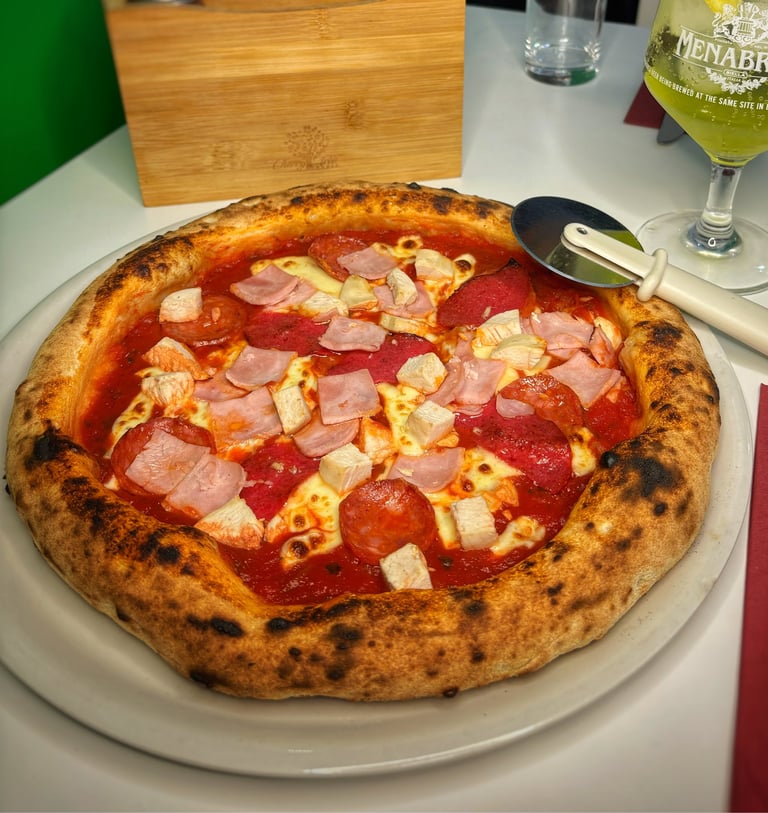 Wood-fired Neapolitan pizza with ham, cheese, and tomato sauce on white plate